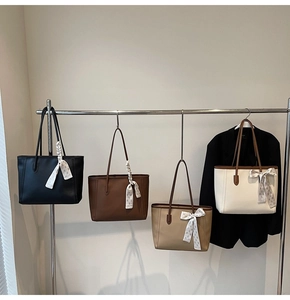 Close-up of four stylish leather tote bags with decorative silk scarves on silver hangers