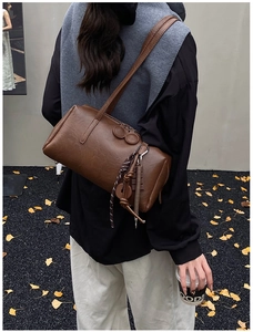 Chic brown oil wax leather barrel bag shown in a stylish autumn street scene setting