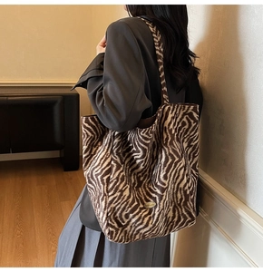Detail of zebra print tote bag with golden Handmade metal tag on textured fabric