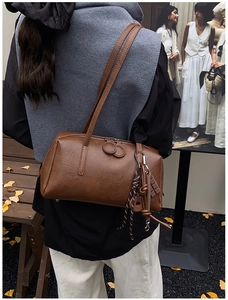 Close-up of vintage brown leather handbag featuring dual handles and decorative rope pendant