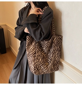 Close-up of zebra pattern tote bag with handmade logo tag on grey blazer outfit