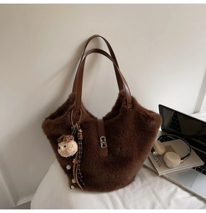 Détail d'un sac cabas en fausse fourrure marron avec anses en cuir et breloque ours