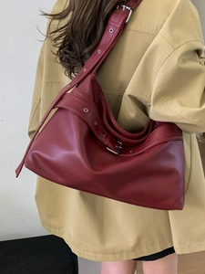 Vintage burgundy leather tote bag with adjustable strap buckles worn by model for casual style
