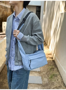 Close-up of light blue nylon crossbody bag with dual zipper pockets and adjustable strap