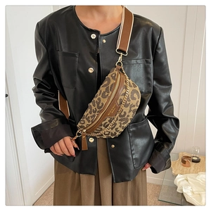Close-up of leopard print chest bag with gold chain and wide brown shoulder strap