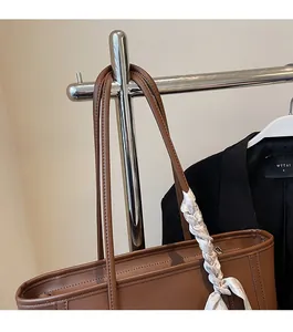 Detailed view of brown tote bag with decorative silk scarf on shoulder strap