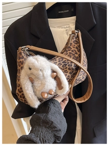 Detail der Schultertasche mit Leopardenmuster, großem Plüschhasen-Anhänger und braunem Griff