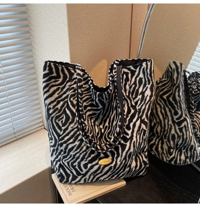 Detailed view of zebra print tote bag with handmade gold metal plaque and woven straps