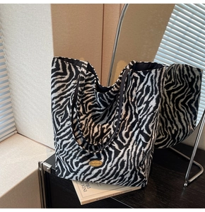Detail of zebra print tote bag featuring a gold handmade logo and black leather straps