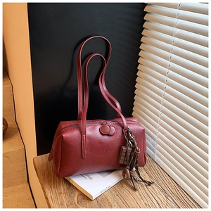 Detail of dark red faux leather Boston bag with chocolate charm and elegant tassels