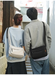 Outdoor lifestyle shot of large capacity nylon crossbody bags in black and cream colors