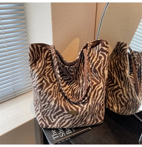 Detail of zebra print tote bag with plush texture and handmade metallic brand plate