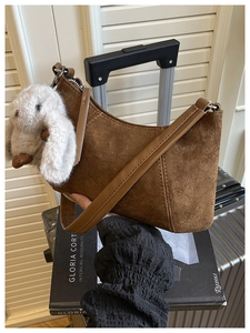 Detail der braunen Wildledertasche mit Ziernähten und niedlichem Plüschhund-Anhänger-Zubehör