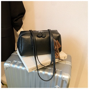 Detail view of black matte leather shoulder bag with decorative fashion charms on silver metal