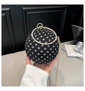 Close-up of black velvet sphere evening bag with white polka dots and gold chain strap
