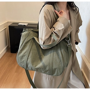 Grote olijfgroene tote bag van gewassen nylon gedragen door model met schouderband