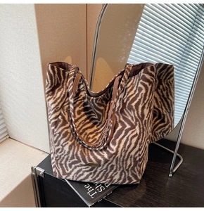 Close-up of zebra pattern tote bag with handmade metal tag on a wooden surface