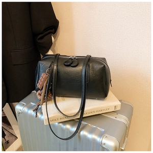 Detail of vintage oil-waxed black underarm bag with chocolate charm and hair tie decor