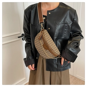 Detailed view of houndstooth crossbody bag with brown leather trim and gold chain