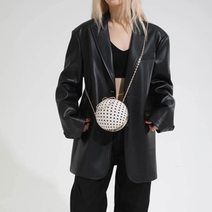 Detailed view of spherical crossbody bag with classic black and white polka dot pattern