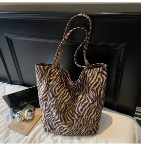 Close-up of zebra print tote bag with handmade metal tag on minimalist white bedding