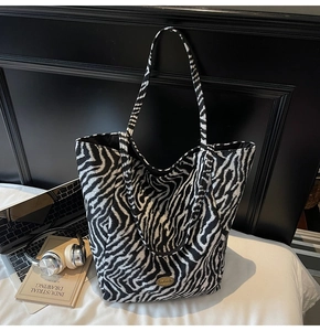 Close-up of zebra print tote bag with plush texture and handmade metal plaque detail