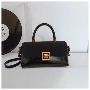 Detail der schwarzen Handtasche mit Materialmix und goldener S-Schnalle auf Podest