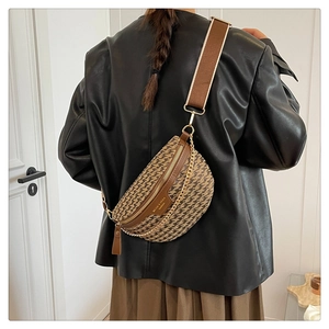 Detail of woven crescent chest bag featuring wide brown strap and gold chain accent