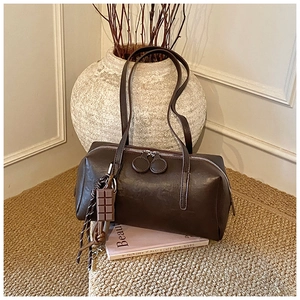 Detail view of dark brown oil wax leather shoulder bag with chocolate pendant and weave cord