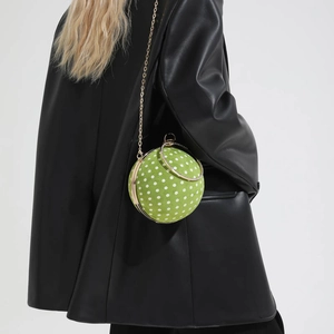 Detail of green polka dot velvet spherical bag with gold chain and crystal handle