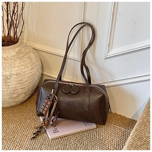 Detail of dark brown faux leather bag with unique chocolate charm and double zipper closure