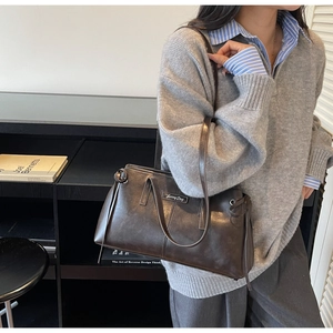 Close-up of retro dark brown shoulder bag with metallic plaque and sleek leather texture