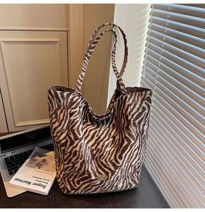 Detail of zebra print tote bag with Handmade label next to a laptop in a cozy office setting