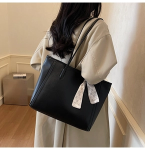 Detail of black matte faux leather tote bag with geometric silk scarf on shoulder
