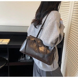 Detail of a deep brown faux leather pillow bag with Hing Day logo and double straps