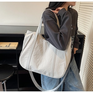 Macro-opname van de witte tote bag van gewassen stof met plooitextuur en brede riem
