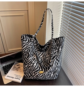 Detail of zebra print canvas tote bag featuring a golden handmade logo on textured fabric