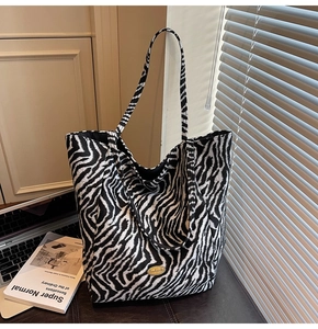 Detail of zebra print canvas tote bag featuring a gold handmade metal tag on the front