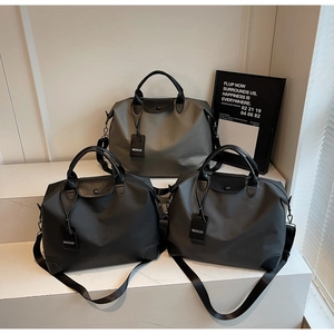 Tre grandi borse da viaggio in nylon nero, grigio e verde oliva con manici in pelle