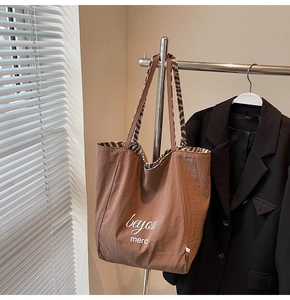 Close-up of large brown tote bag featuring beyou merci print and leopard print lining