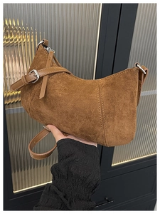 Detailansicht der braunen Wildleder-Halbmondtasche mit sichtbaren Nähten und Silberbeschlägen