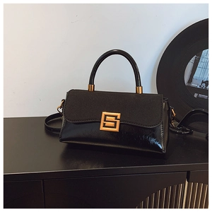 Details einer schwarzen Retro-Handtasche aus glänzendem Lackleder und mattem Wildleder