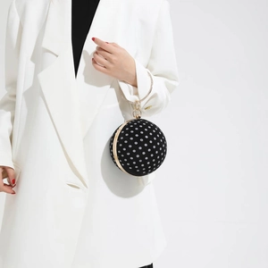 Detailed view of a mini spherical evening bag with black and white polka dots and gold ring handle