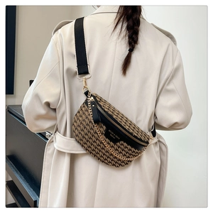Detail of houndstooth crossbody bag with gold chain and black leather trim on model