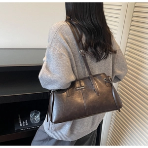 Detail view of brown matte leather shoulder bag with side tassels and silver logo