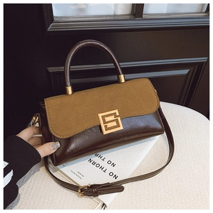 Detail einer braunen Patchwork-Handtasche mit goldener Metallschnalle auf weißem Ständer