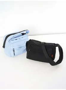 Detail view of nylon crossbody messenger bags in sky blue and black colors
