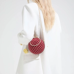 Spherical red velvet evening bag with white polka dots and a rhinestone metal handle