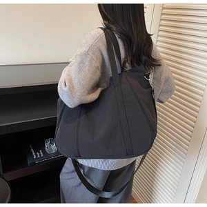 Detailweergave van grote zwarte gewassen stoffen draagtas gedragen door een model in kamer
