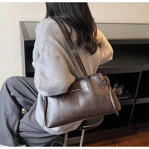 Detail view of large dark brown leather tote bag with Sunny Day logo and adjustable strap